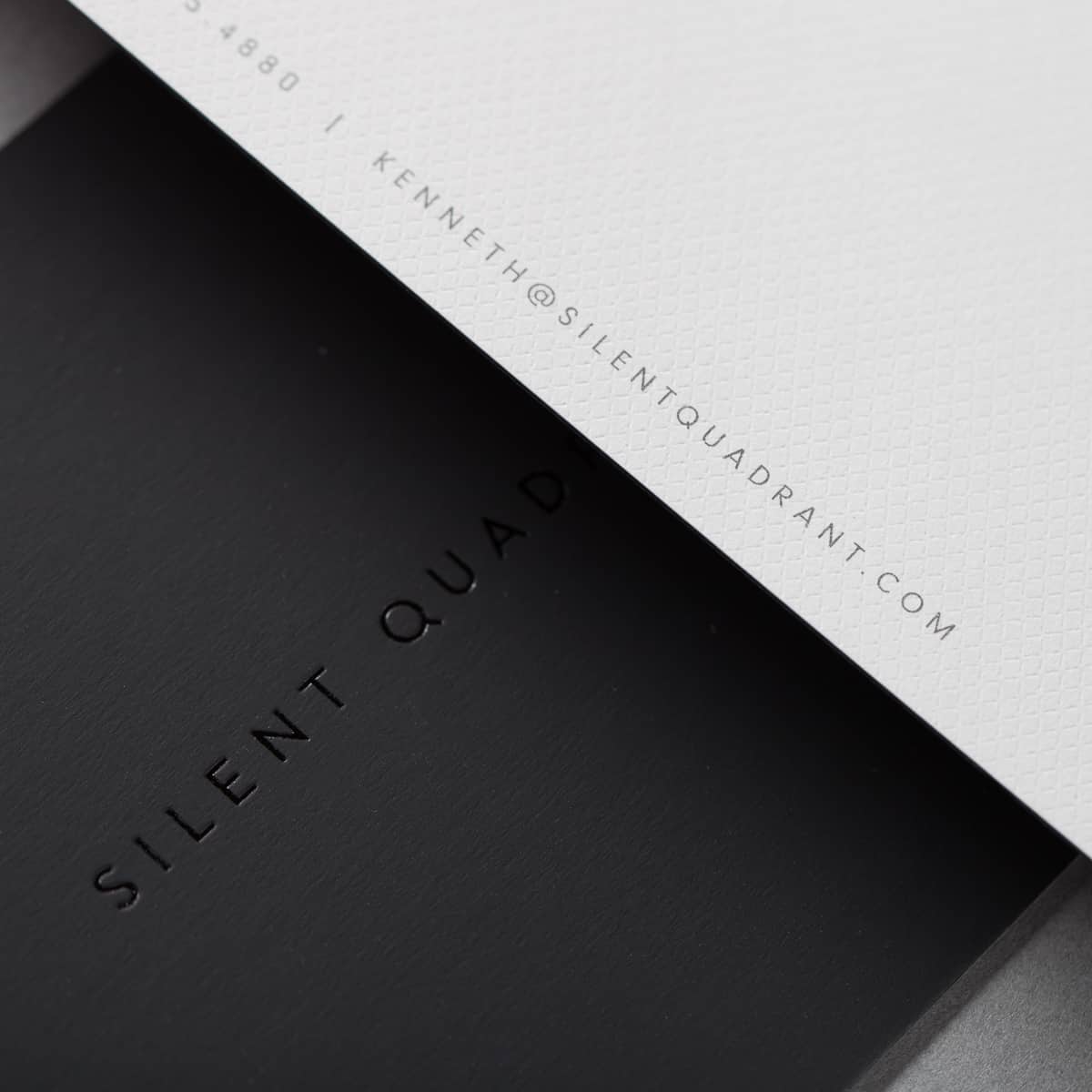 Macro close-up of blind deboss depth on textured cream stationery