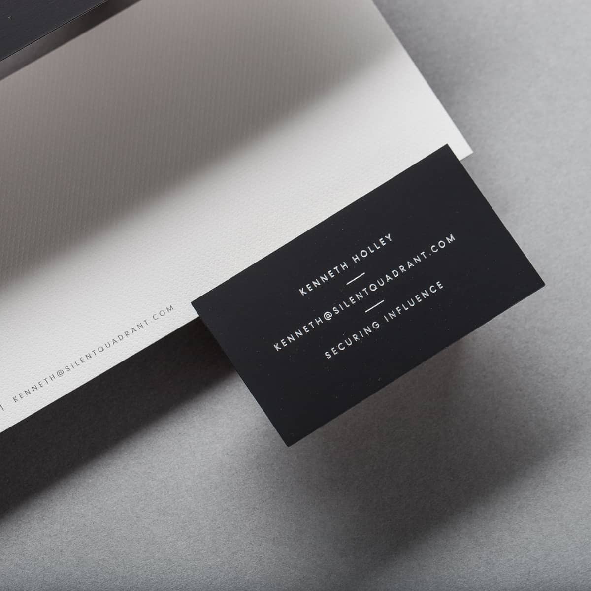 Silent Quadrant executive business card resting on textured linen letterhead
