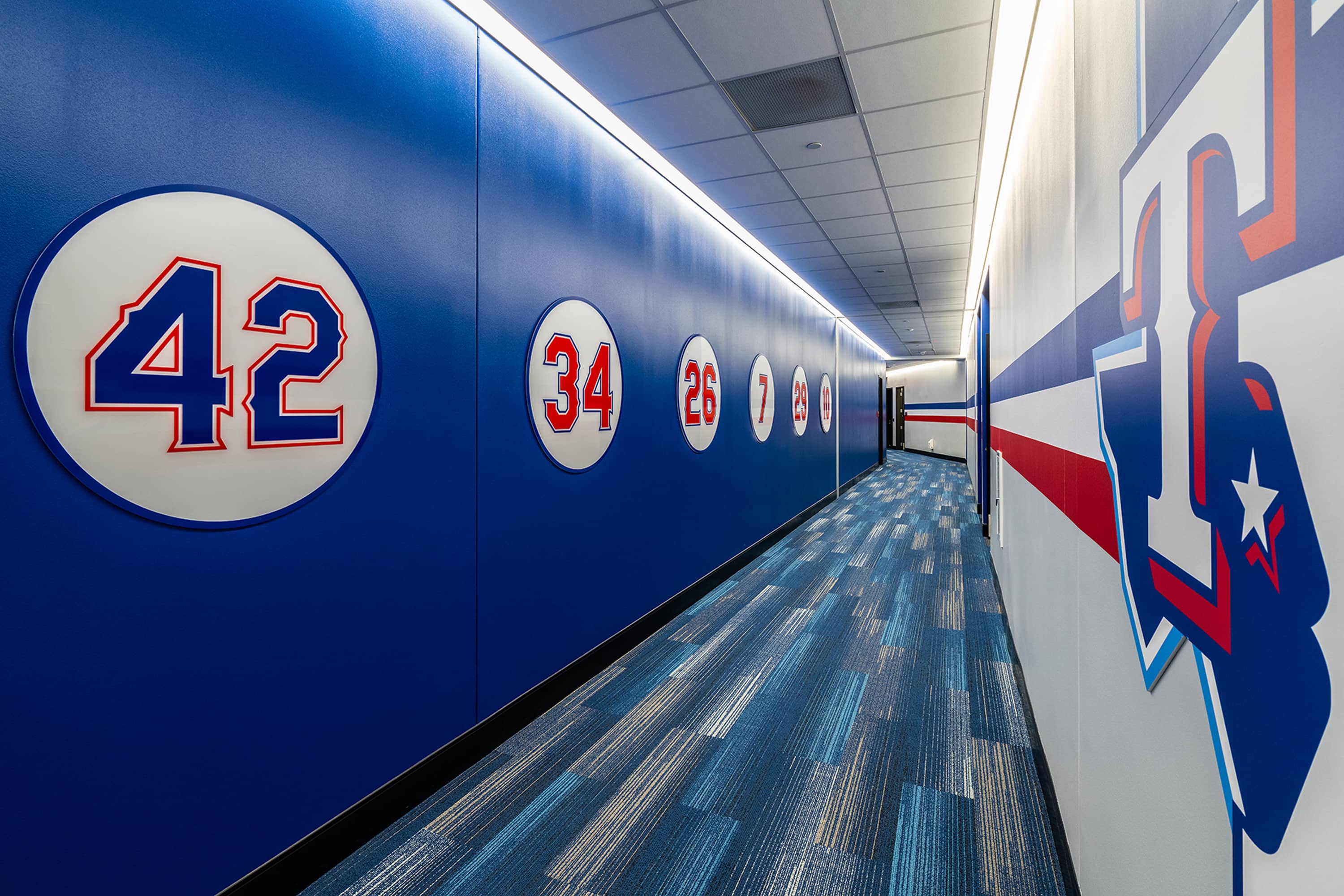 Dimensional historic numbers in white roundels along cove-lit blue corridor wall