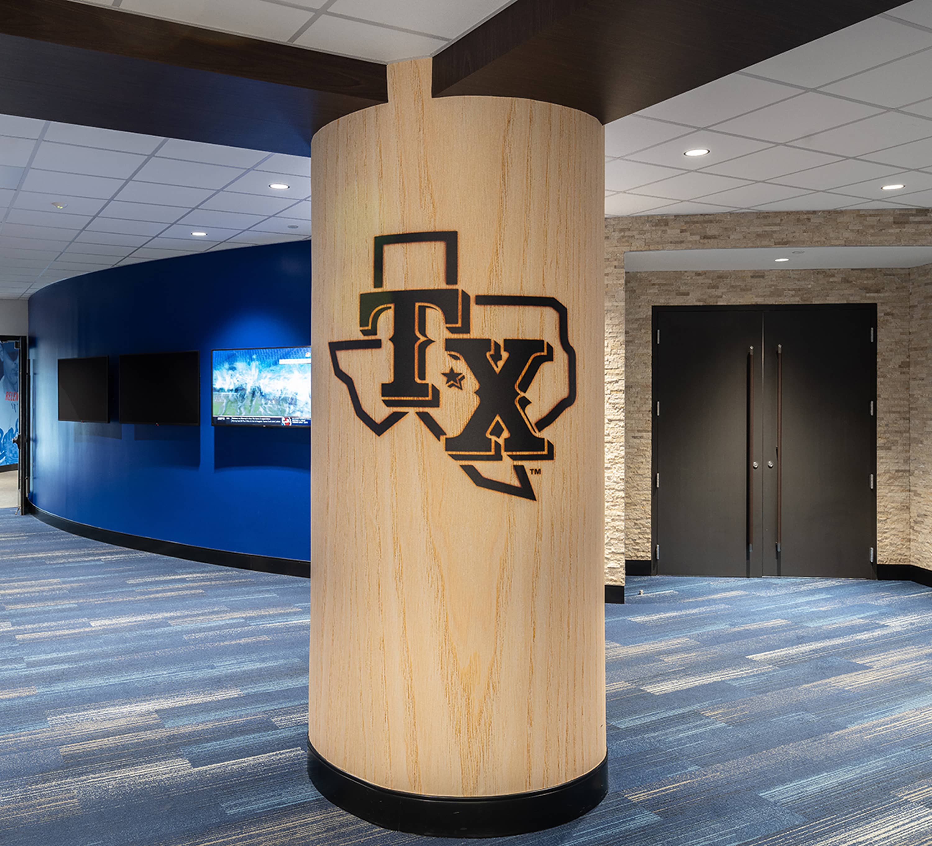 Circular structural pillar clad in wood veneer with dimensional TX logo