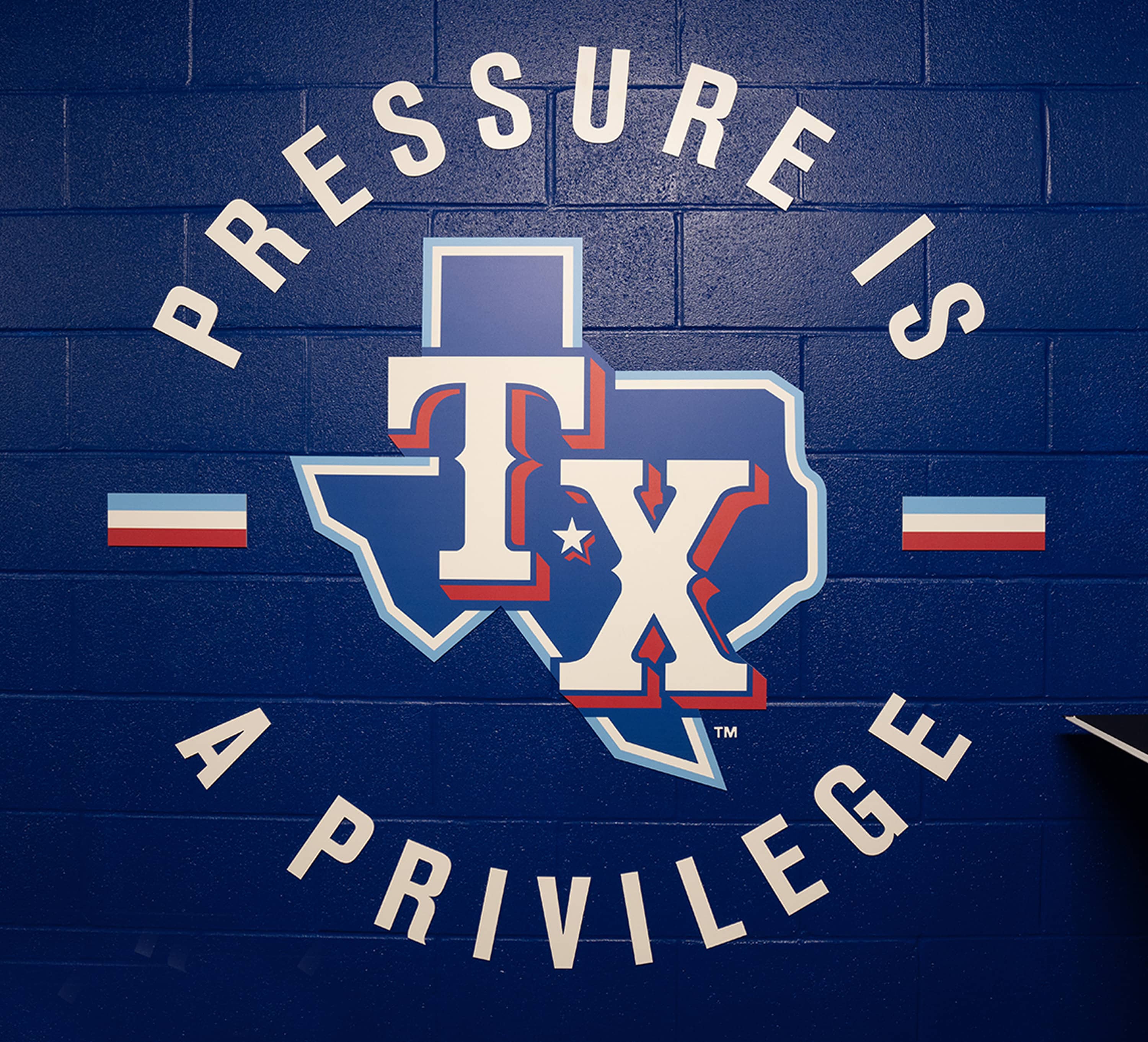 Pressure is a Privilege typographic mural painted on blue cinderblock wall