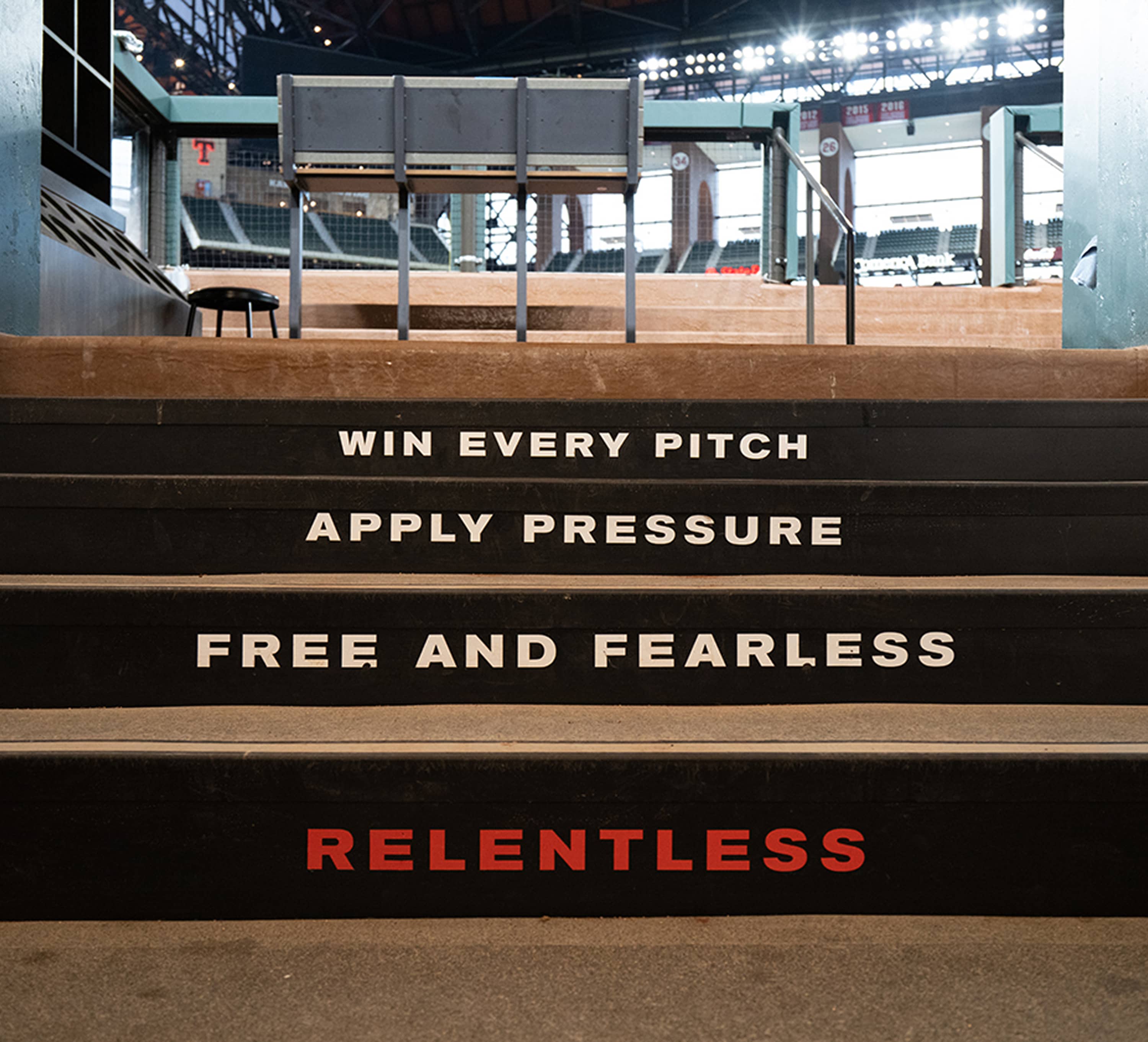 Concrete dugout stair risers reading Relentless, Free and Fearless, Apply Pressure, and Win Every Pitch